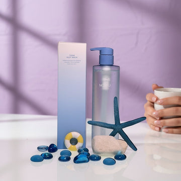 Assemble K - Play .Try .Glow Clear Body Serum 290ml, a clear, lightweight serum in a pump bottle with blue accents. Features a blue starfish and decorative stones.