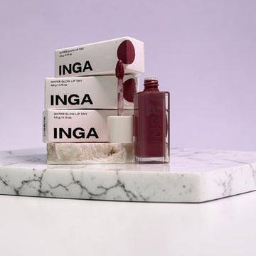 Assemble K - Play .Try .Glow INGA Water Glow Lip Tint in Rosy Rose shade, featuring a clear bottle with applicator and stacked product boxes.