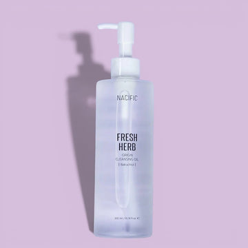 Assemble K - Play .Try .Glow holds NACIFIC Fresh Herb Origin Cleansing Oil with Bakuchiol, a clear oil in a frosted bottle with a pump dispenser.