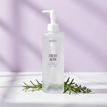 Assemble K - Play .Try .Glow holds NACIFIC Fresh Herb Origin Cleansing Oil with Bakuchiol, a clear oil in a frosted bottle with a pump dispenser.
