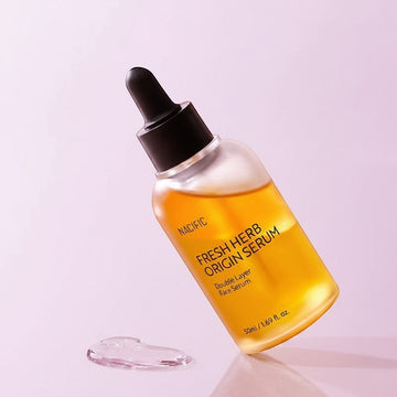Assemble K - Play .Try .Glow: Nacific Fresh Herb Origin Serum, a double-layer face serum in a clear bottle with a black dropper. Golden liquid.
