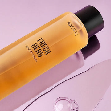 Assemble K - Play .Try .Glow NACIFIC Fresh Herb Origin Toner, a golden-hued liquid in a clear bottle with a black cap, featuring text labels.
