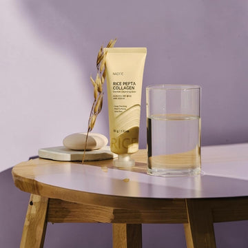 Assemble K - Play .Try .Glow NACIFIC Rice Pepta Collagen Sherbet Cleansing Balm 80g, a pale yellow tube with text, next to a glass of water.
