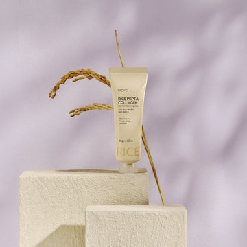 Assemble K - Play .Try .Glow NACIFIC Rice Pepta Collagen Sherbet Cleansing Balm 80g tube on a pedestal with wheat stalks.
