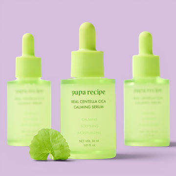 Assemble K - Play .Try .Glow: Papa Recipe Real Centella Cica Calming Serum in a green glass bottle with a dropper, featuring calming, soothing, and moisturizing properties.