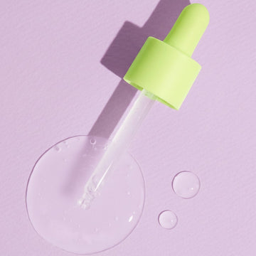 Assemble K Real Centella Cica Calming Serum with pipette and serum drops on a light green background.