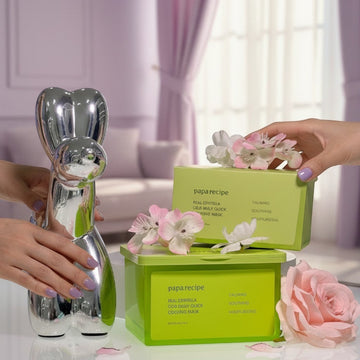 Assemble K - Play .Try .Glow: Papa Recipe Real Centella Cica Daily Quick Cooling Mask packaging with pink flowers and a silver sculpture.