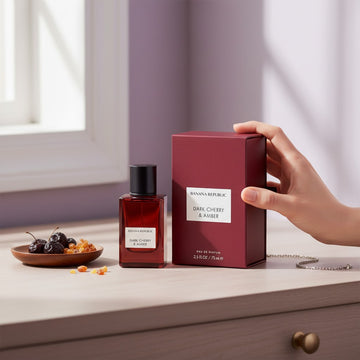Assemble K - Play .Try .Glow Banana Republic Dark Cherry & Amber perfume bottle and box on a wooden table with cherries.