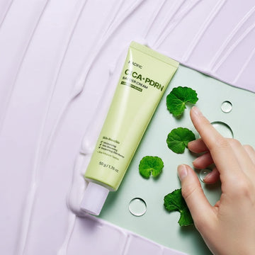 Assemble K - Play .Try .Glow Cica PDRN Barrier Cream tube with Centella Asiatica leaves and water droplets. Soothes and strengthens skin barrier.