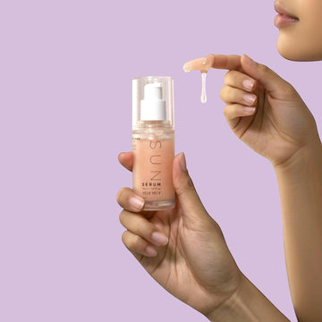 Assemble K - Play .Try .Glow hydrating sunserum with a lightweight, peach-toned texture held by a model.