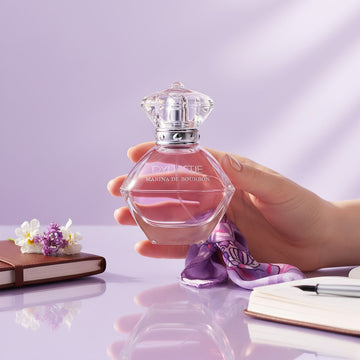 Assemble K - Play .Try .Glow Marina De Bourbon Dynastie Mademoiselle perfume bottle held in a hand on a purple desk.