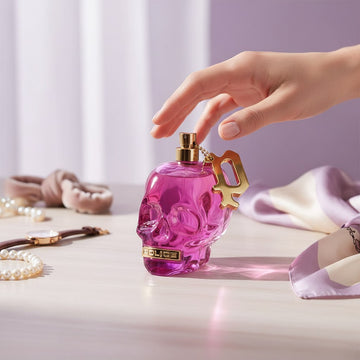 Assemble K - Play .Try .Glow Police To Be Free To Dare perfume in a pink skull-shaped glass bottle on a vanity table.