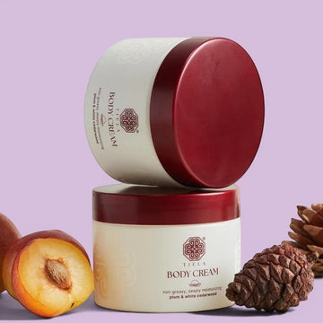 Assemble K - Play .Try .Glow Tiela Body Cream in a cream-colored jar with a dark red lid, featuring a plum and white cedarwood scent.