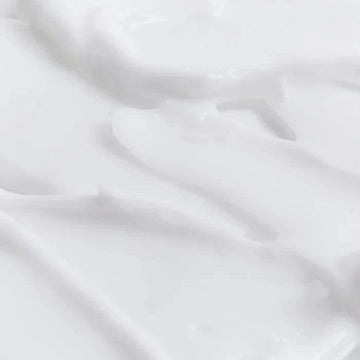 Assemble K - Play .Try .Glow Tiela Body Cream in a cream-colored jar with a dark red lid, featuring a plum and white cedarwood scent.