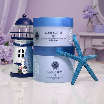 Assemble K - Play .Try .Glow Tiela Perfume Therapy Body Scrub Pure 250g in light blue packaging with a lighthouse and starfish decor.