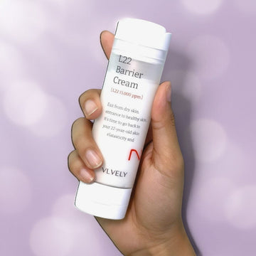 Assemble K - Play .Try .Glow VELY VELY L22 Barrier Cream 50ml, a white pump bottle with red lettering, held by a hand against a lavender background.